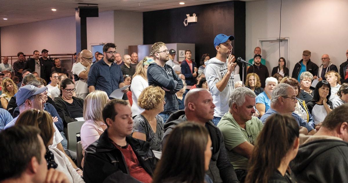 Photo de l'assemblée générale du STT de Barry Callebaut. Personne à casquette bleu au micro dans une grande foule.