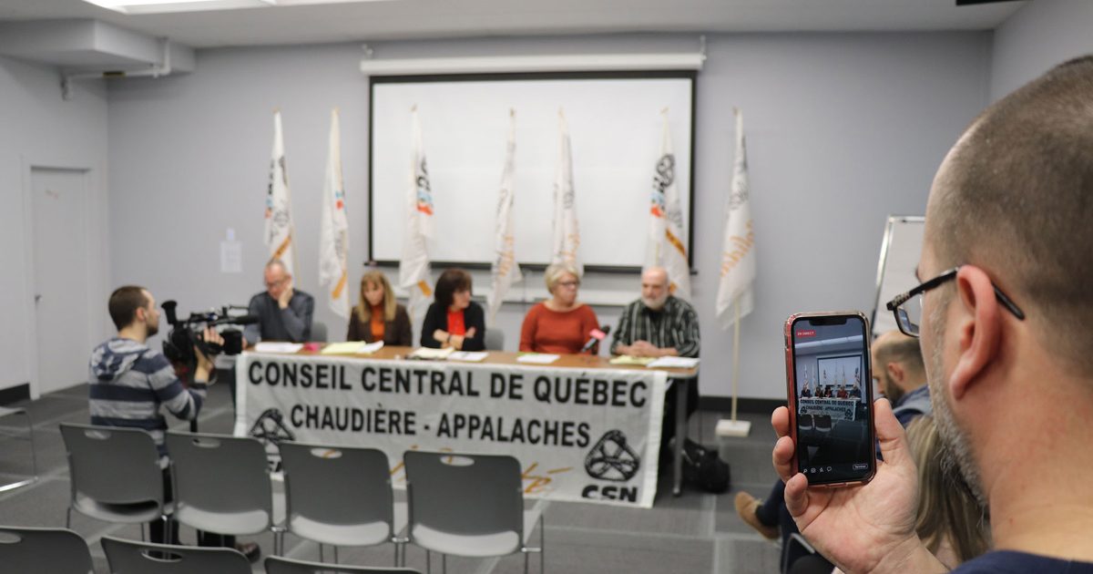 Photo de conférence de presse au CCQCA, 5 personnes à une table, une personne qui filme sur son cellulaire