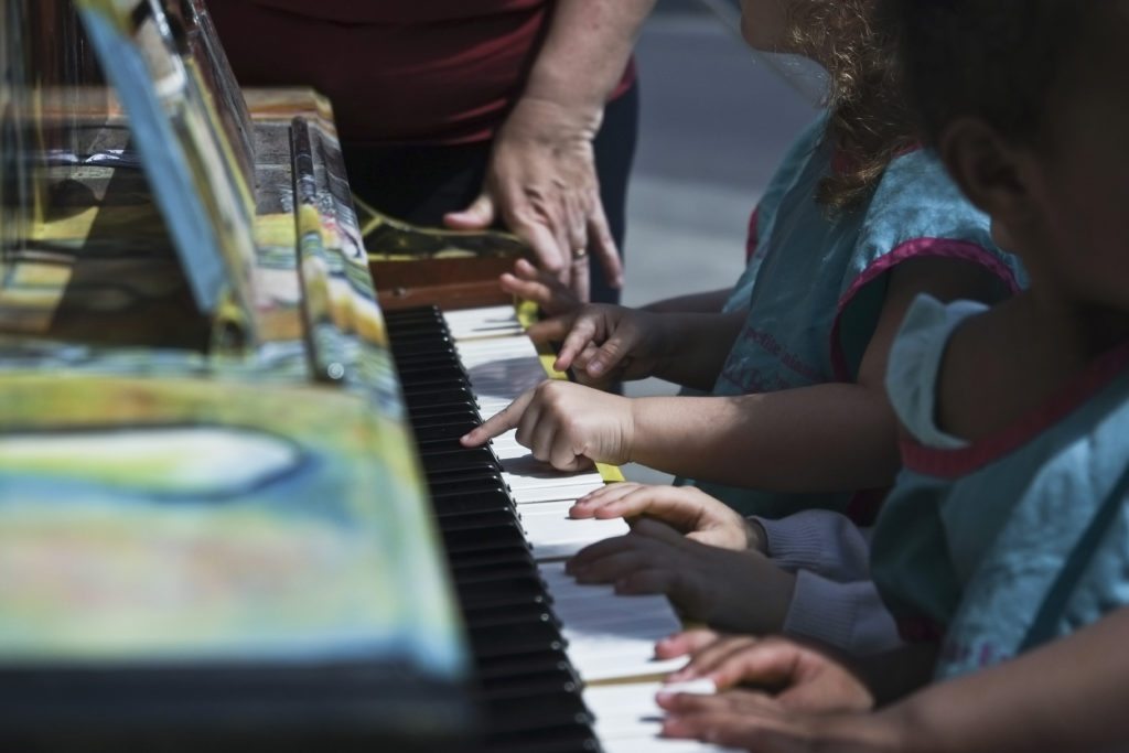 Les jeunes de l’installation Minime font une petite pause au piano en libre-service sur le parquet de la Maison de la Culture de Montréal-Nord