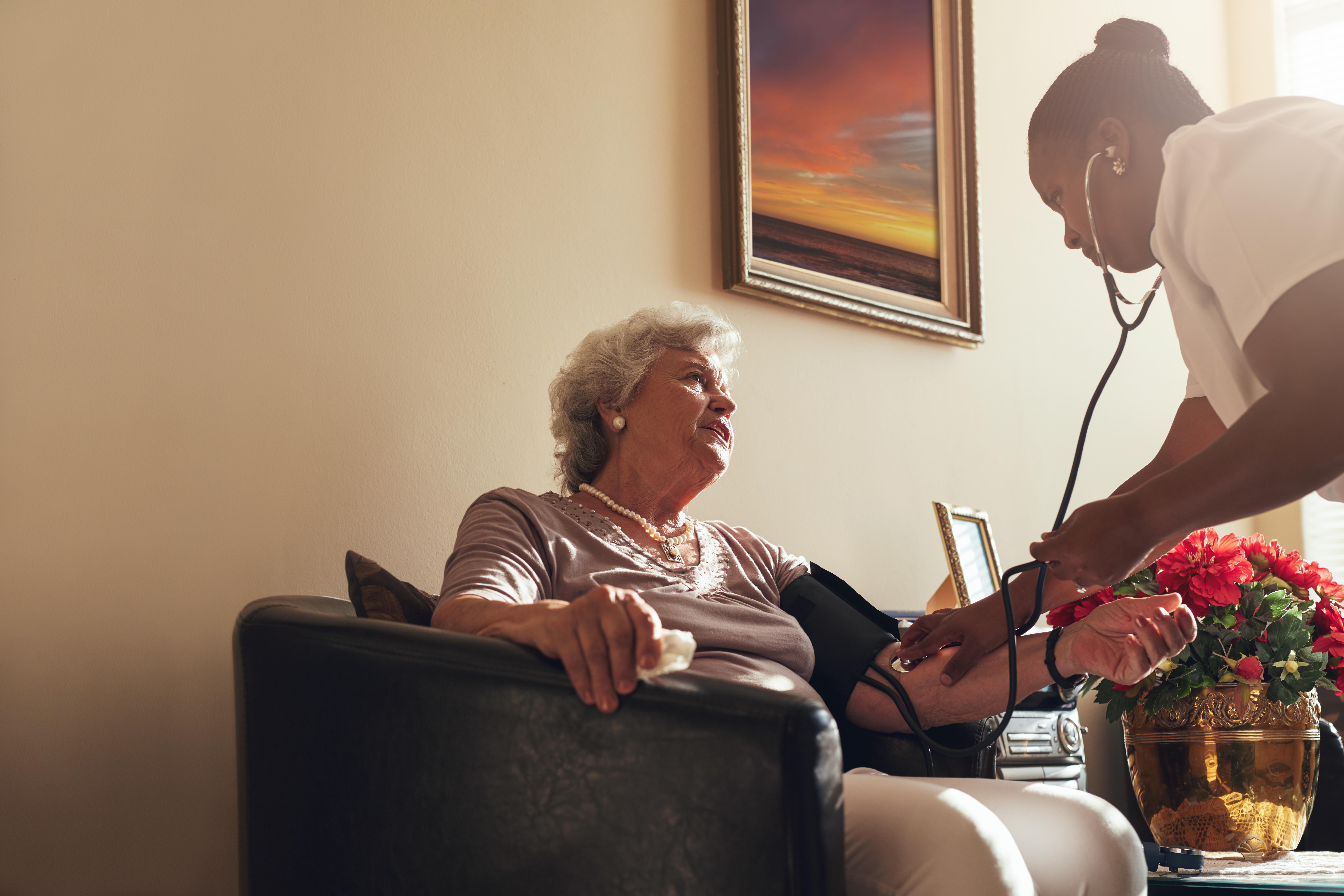 Home healthcare nurse checking blood pressure of senior woman