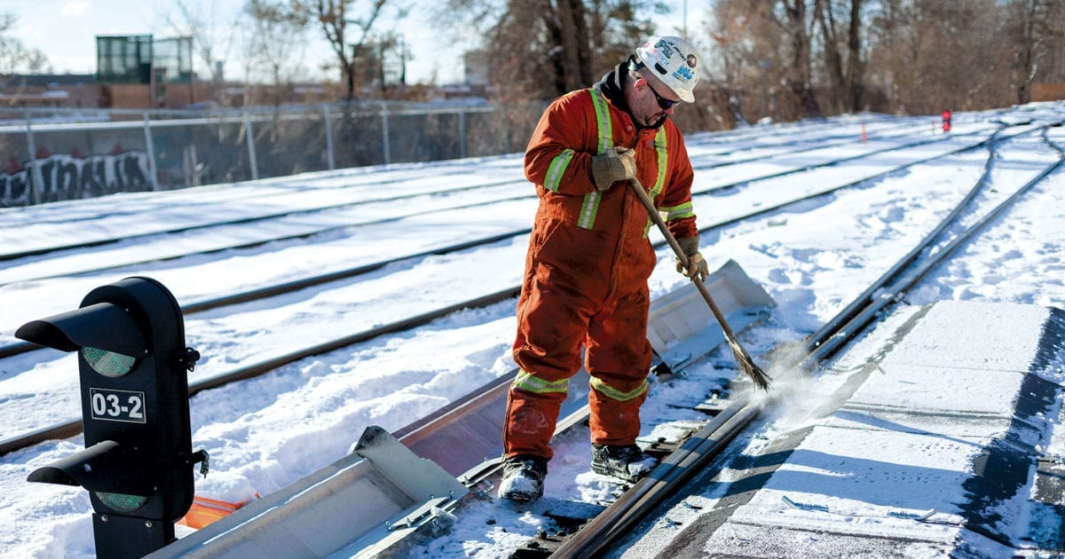 Travailleur de la construction nettoyant un chemin de fer l'hiver