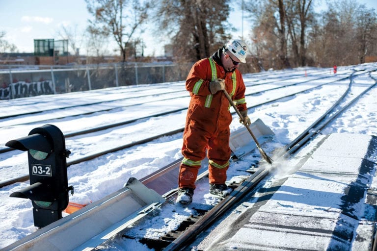 Travailleur de la construction nettoyant un chemin de fer l'hiver