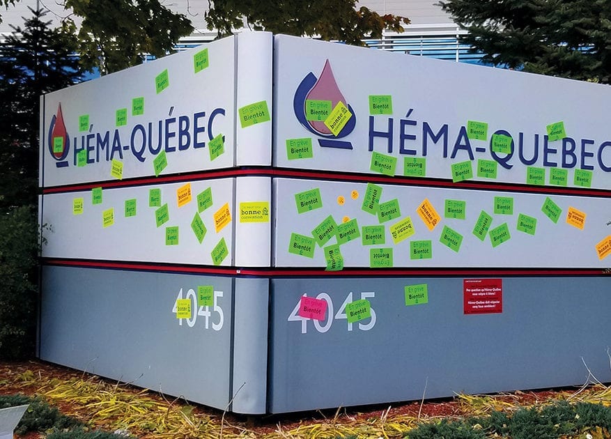 Pancarte d'Héma-Québec couverte d'autocollants CSN