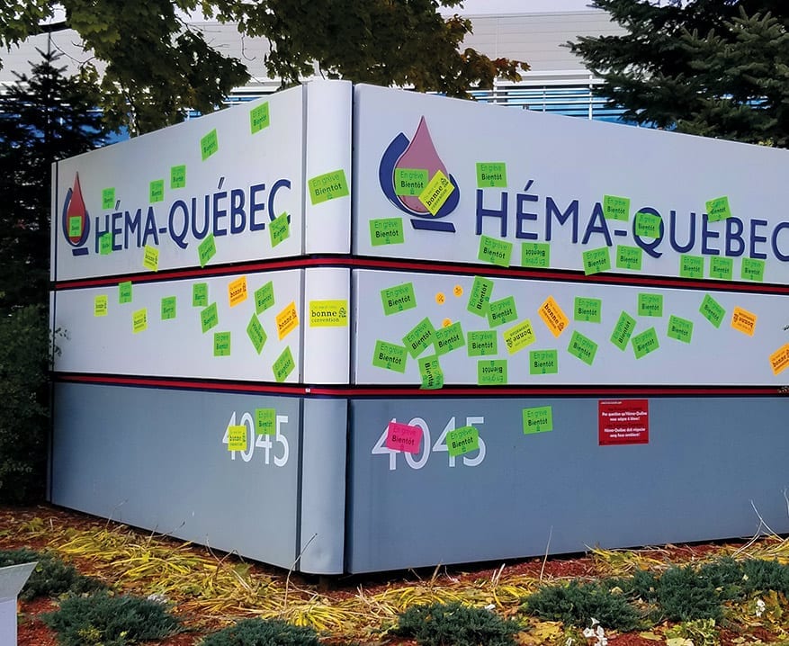 Pancarte d'Héma-Québec couverte d'autocollants CSN