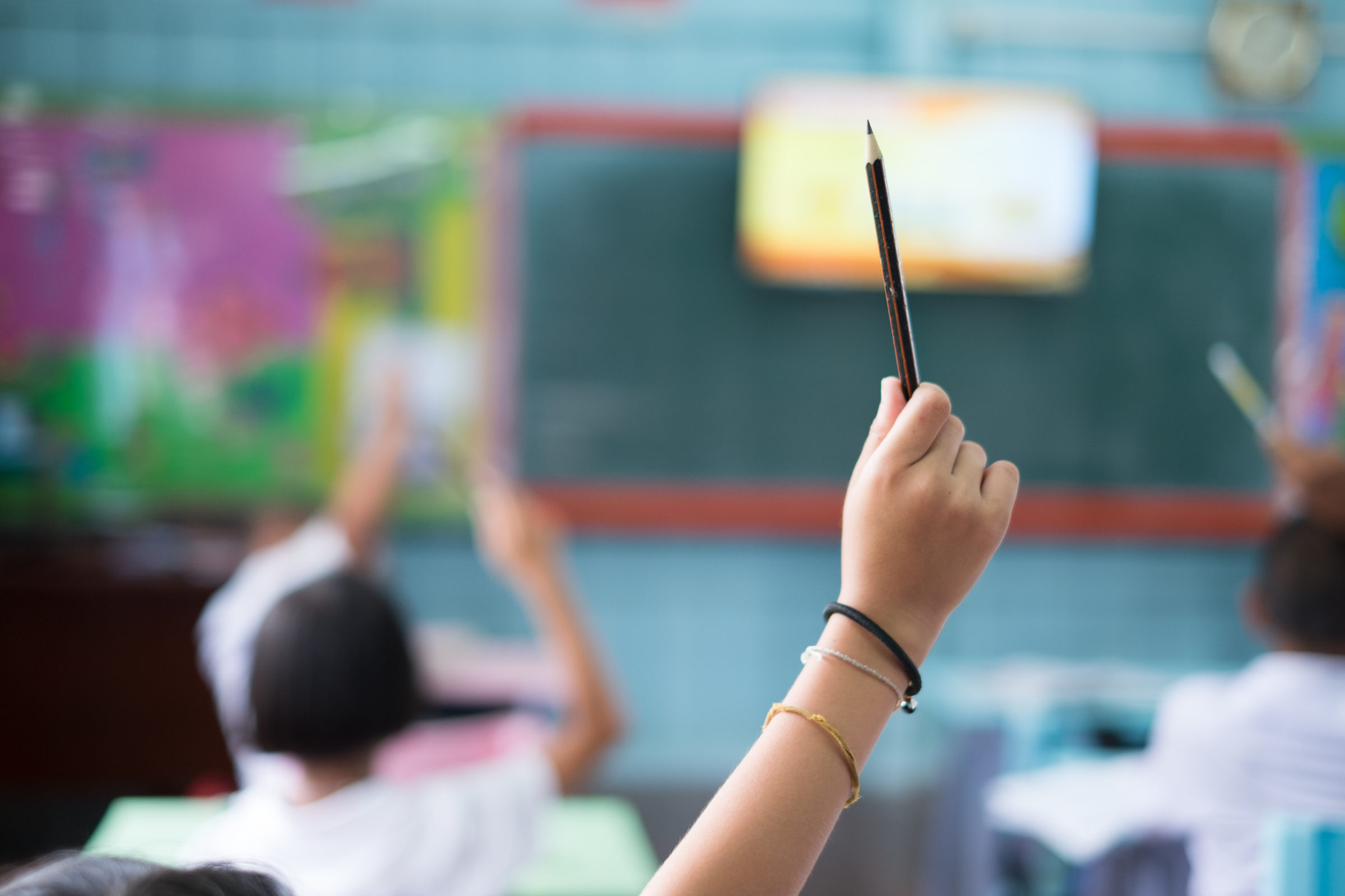 Student hands up asking a question in class at the elementary school. Education concept.
