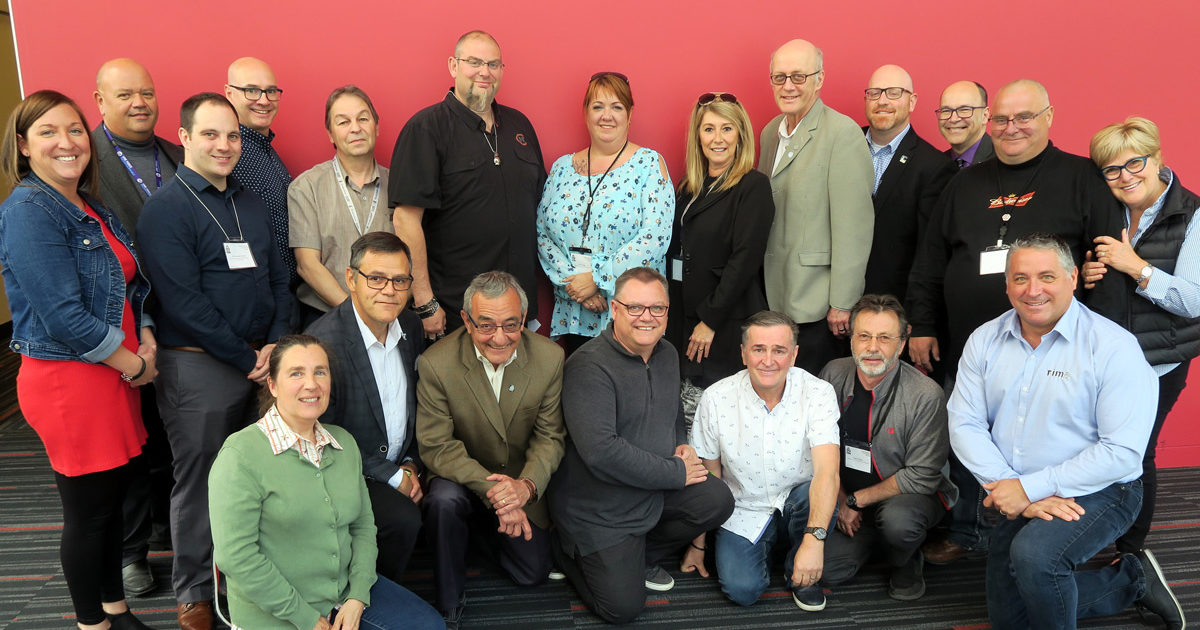 Les membres du groupe de travail du Camp vol d'été-Leucan-CSN devant un mur rouge.