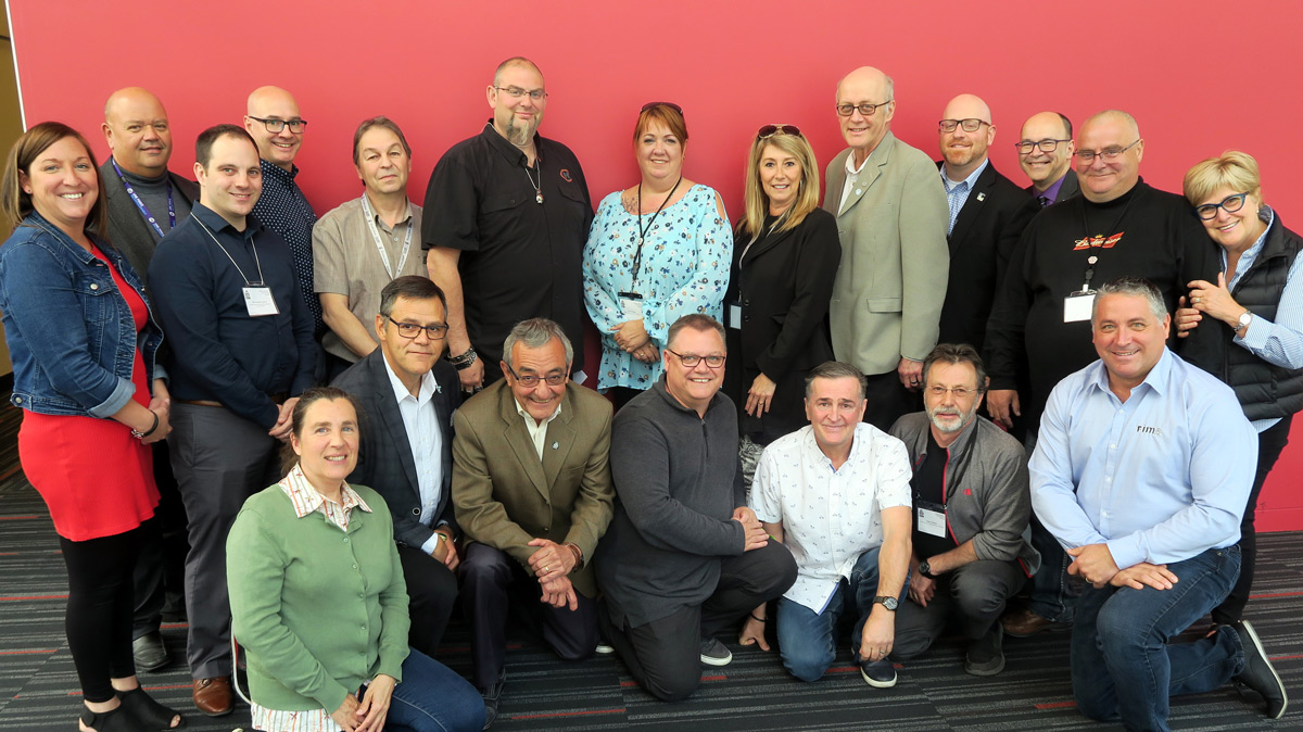 Les membres du groupe de travail du Camp vol d'été-Leucan-CSN devant un mur rouge.