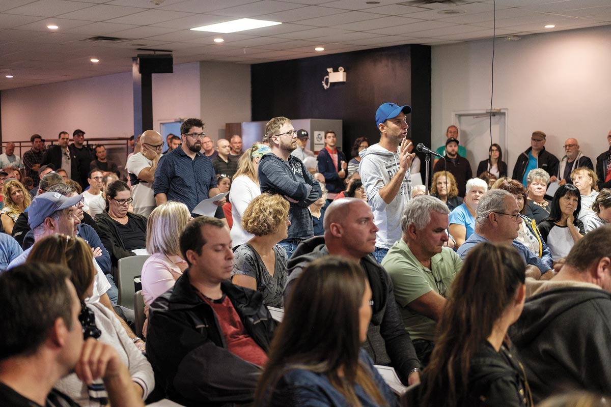 Photo de l'assemblée générale du STT de Barry Callebaut. Personne à casquette bleu au micro dans une grande foule.