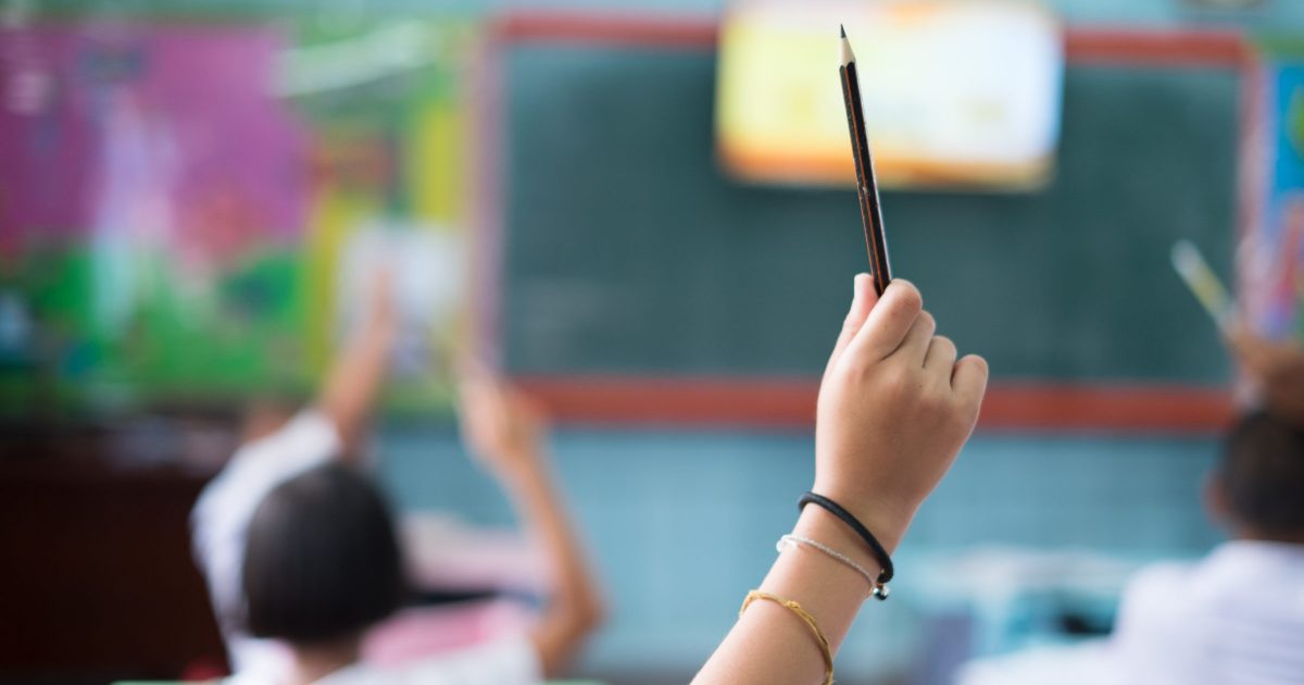 Student hands up asking a question in class at the elementary school. Education concept.